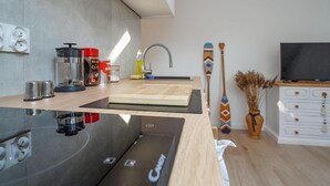 A modern kitchen with a built-in stove, a cutting board, and various kitchen appliances. - Cozy apartment in Dziwnów with WiFi (Dziwnów)