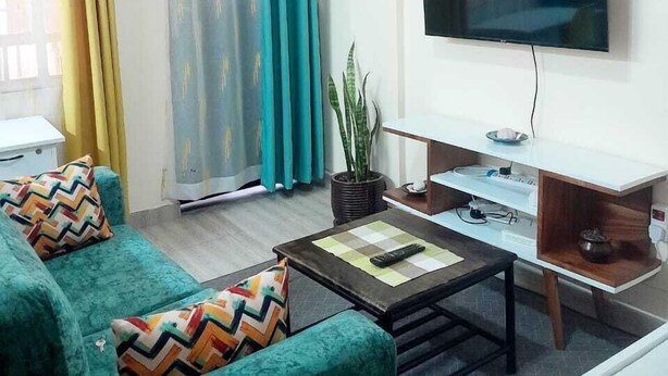 Una sala de estar con sofá, mesa de centro, televisor y cortinas.