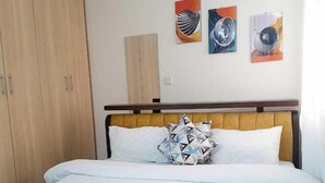 Un dormitorio con una cama, un armario de madera y tres obras de arte en la pared.