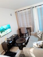 Una sala de estar con sofá, mesa de centro, televisor y un comedor con una silla y mesa.