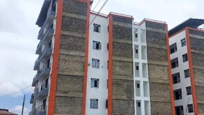 Un edificio residencial de varios pisos con balcones, un vestíbulo central y fachada de ladrillo.