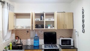 Cocina compacta equipada con estufa a gas, microondas y un refrigerador pequeño.
