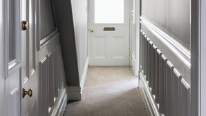 A hallway with a white door at the end, white trim, and a carpeted floor. - Luxury Apartment on Stuart Street (Dunedin)
