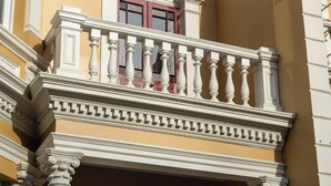 A building with a balcony, columns, and a window with a red frame. - Luxury Apartment on Stuart Street (Dunedin)