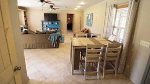 A dining area with a table and chairs, a ceiling fan, and a bookshelf in the background. - Cozy Cove Grand Lake Home - Near cove with ramp (Vinita)