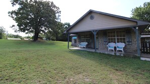 A building with a porch and two chairs. - Cozy Cove Grand Lake Home - Near cove with ramp (Vinita)