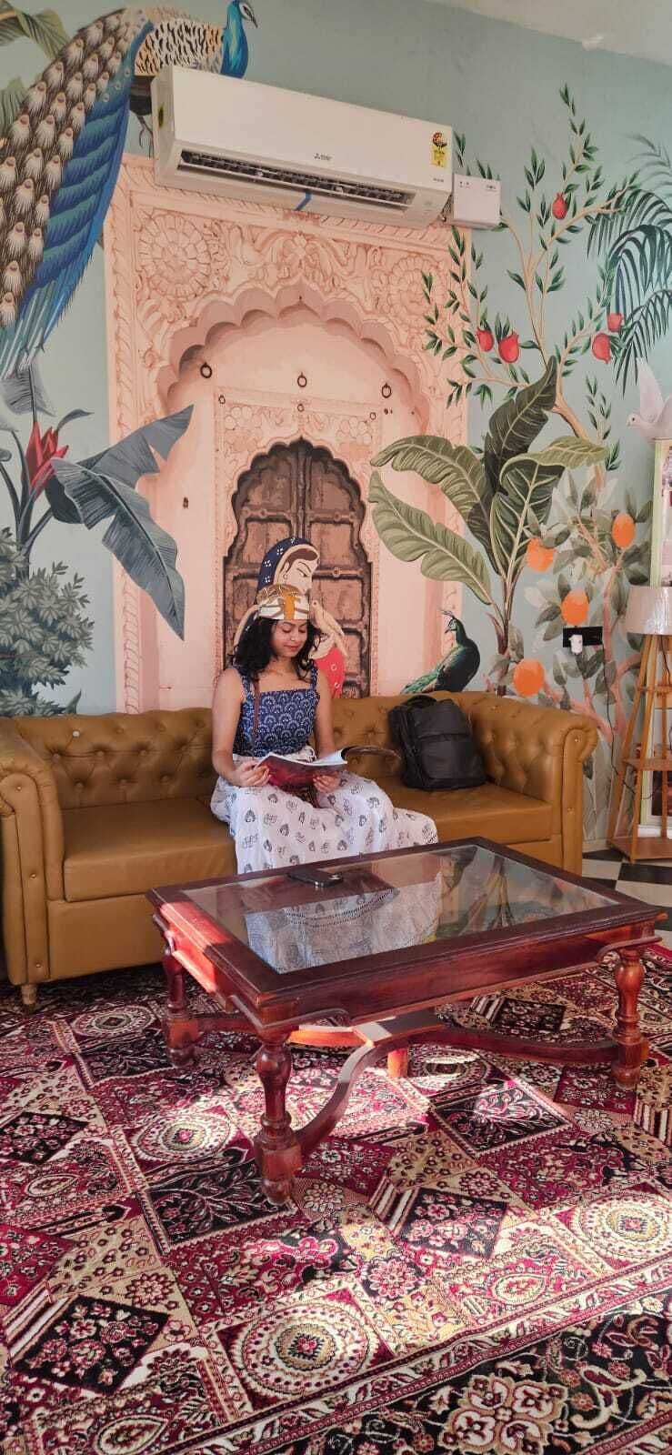 A room with a brown sofa, a glass coffee table, and a patterned carpet.
