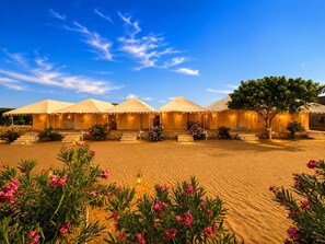 A desert resort with multiple tents and a sandy landscape.