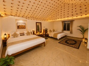 A hotel room with two beds, a large mirror, a wall-mounted picture, and a patterned carpet. - Robin Desert Safari Camp  (Jaisalmer)