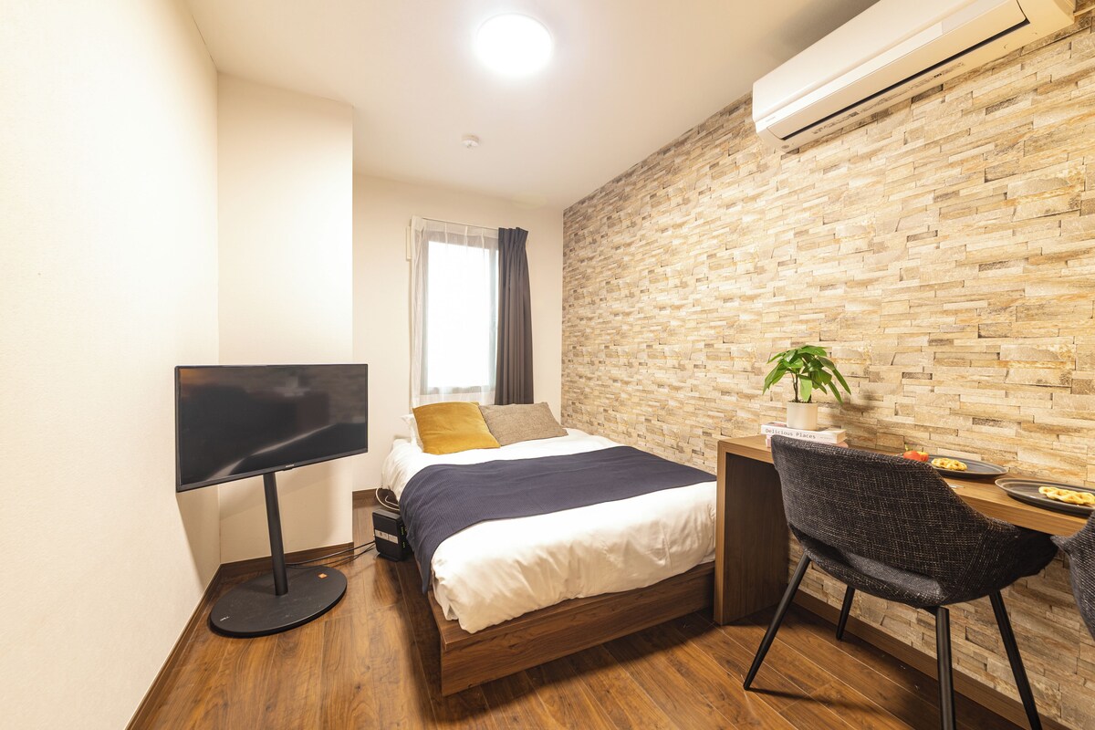 Ein Schlafzimmer mit Bett, Schreibtisch, Stuhl, Fernseher und Klimaanlage.