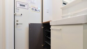A hotel room with a check-out time sign, a door with a black panel, and a white cabinet with shelves.