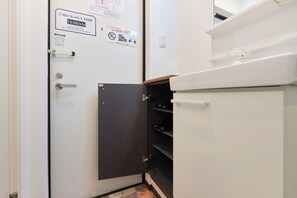 Ein Hotelzimmer mit Hinweisschild für die Ausreisezeit, einer Tür mit schwarzem Einsatz und einem weißen Schrank mit Regalen.