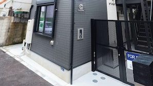 A modern two-story building with a black tiled facade, a black gate, and a visible staircase. - Le Cocon Nakarokugo by Tranova (Tokyo)
