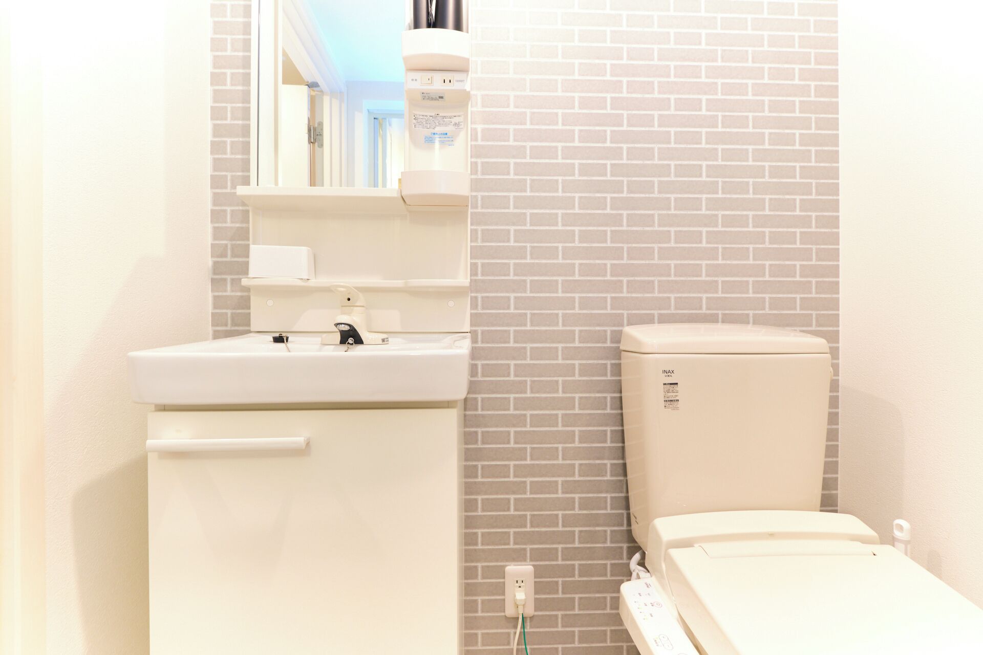 A bathroom with a white sink, a mirror, a toilet, and a power outlet.