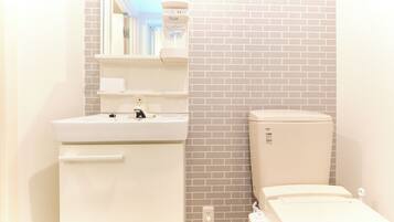 A bathroom with a white sink, a mirror, a toilet, and a power outlet.