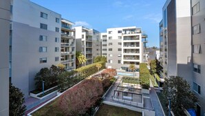 A modern apartment complex with multiple balconies, a central courtyard, and surrounding greenery.