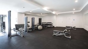 A gym with various exercise equipment, a bench press, dumbbells, and a squat rack.
