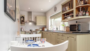 A kitchen with white cabinets, a microwave, and a dining table with chairs. - Beautiful 3BD Fam Retreat in Oxfordshire (Chipping Norton)