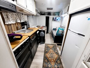A compact kitchen with a stove, sink, and a small dining area. - VINTAGE RV & SPA Experience for 3 (Dover)