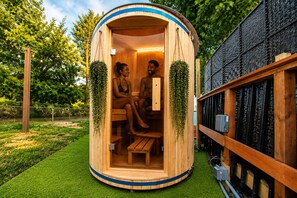 A wooden sauna with two benches, surrounded by greenery and a black mesh wall. - VINTAGE RV & SPA Experience for 3 (Dover)