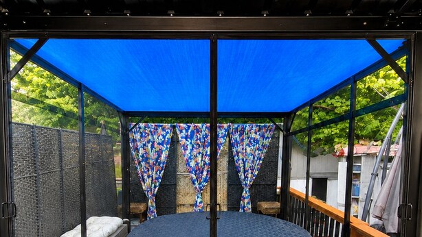 A circular outdoor seating area with a round table and benches, surrounded by a wooden deck and a blue canopy. - VINTAGE RV & SPA Experience for 3 (Dover)