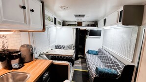 A compact RV interior with a kitchenette, a dining area, and a sleeping space. - VINTAGE RV & SPA Experience for 3 (Dover)