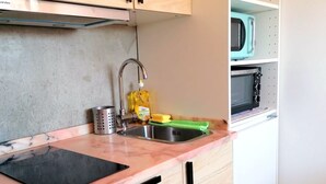 A kitchen with a sink, a faucet, a dish soap bottle, a colander, and a green cutting board. - Cq15 Cozy Studio Next to HUC (Coimbra)