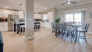 A spacious kitchen with white cabinets, a central island with stools, and a dining area with a table and chairs. - Big Pine Paradise: Beautiful Updated 4BR Canal Front Home, Pool, Dockage, Easy Gulf/Atlantic Access (Big Pine Key)