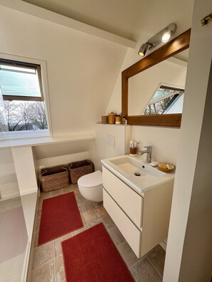 A modern bathroom with a window, a sink, a toilet, and two baskets. - Nid Douillet Les Mouettes, vue sur mer (Fouesnant)