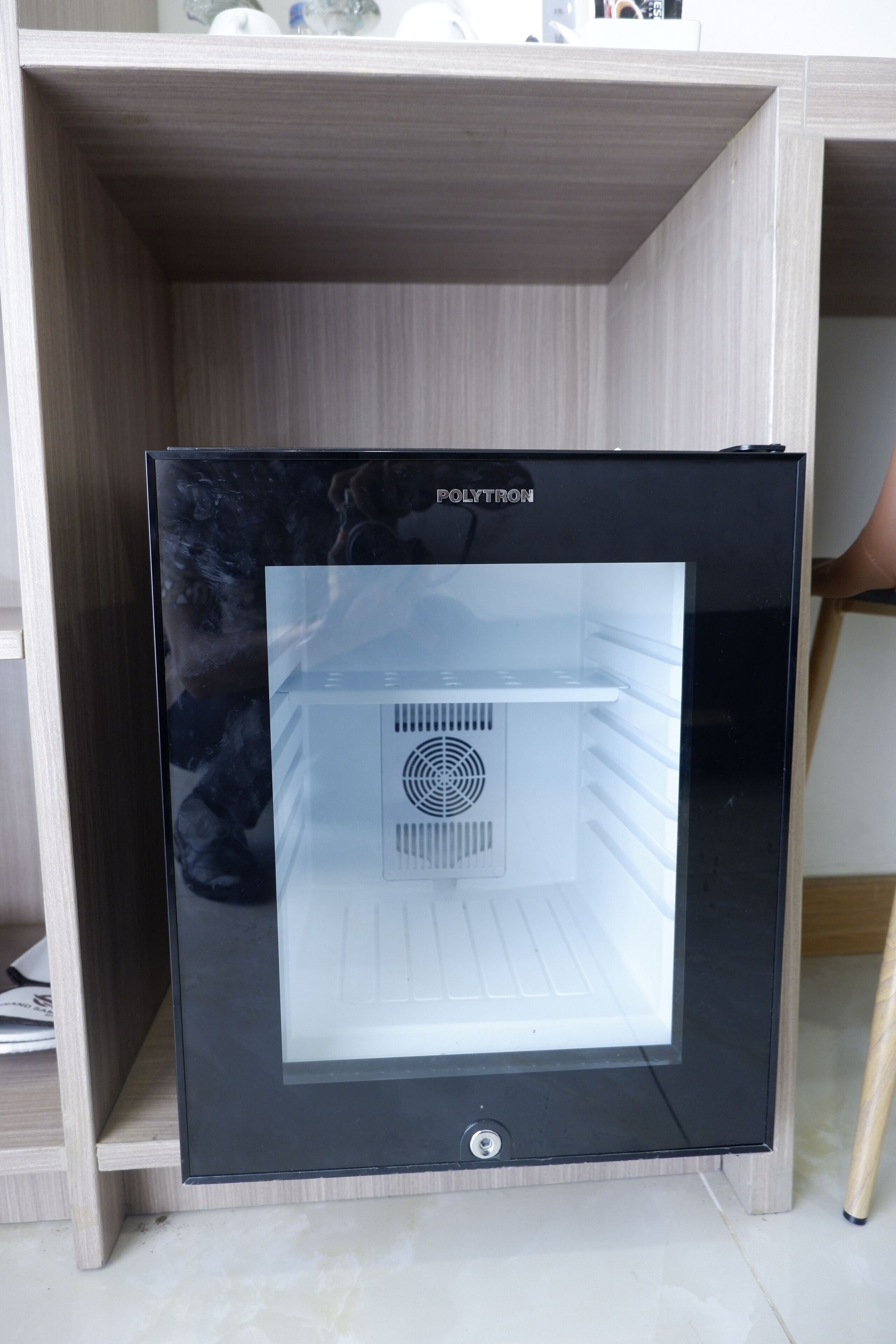 Ein schwarzer Kühlschrank mit sichtbarem Markennamen, der in einem Holzkorpus steht.