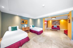Een hotelkamer met twee bedden, een houten dressoir en een rode bank.