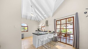A spacious kitchen with a central island, white bar stools, and a large sliding glass door leading to an outdoor area.