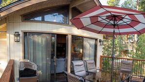 Eine Terrasse mit Gartenmöbeln, einem Grill und einem großen Sonnenschirm.