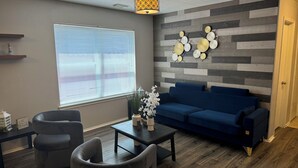 A modern living room with a blue sofa, two armchairs, a coffee table, and a decorative wall with wooden panels. - Modern Cozy Retreat in Katy, TX (Katy)