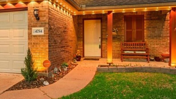 A two-story house with a brick facade, a covered porch, and a well-maintained lawn. - Modern Cozy Retreat in Katy, TX (Katy)