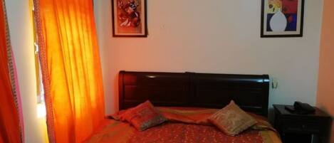 A bedroom with a bed, a nightstand, and two framed pictures on the wall.