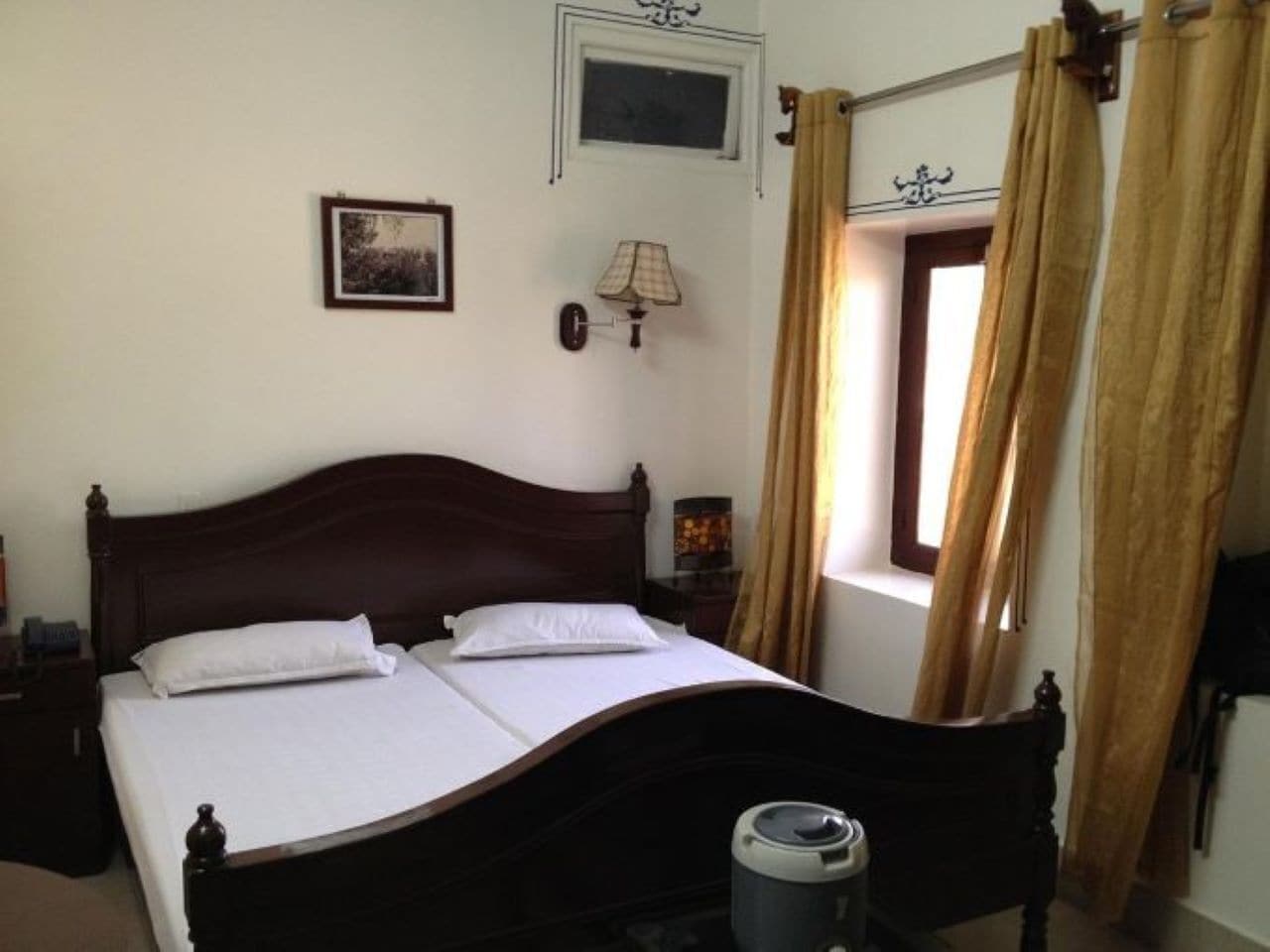 A double bed with a wooden headboard, a bedside lamp, and a window with curtains.