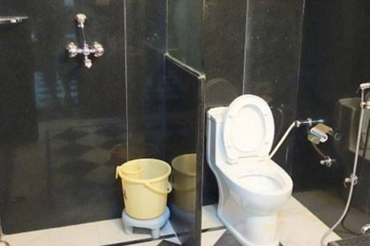 Ein Badezimmer mit schwarz-weiß kariertem Boden, einer weißen Toilette und einer Glasabtrennung.