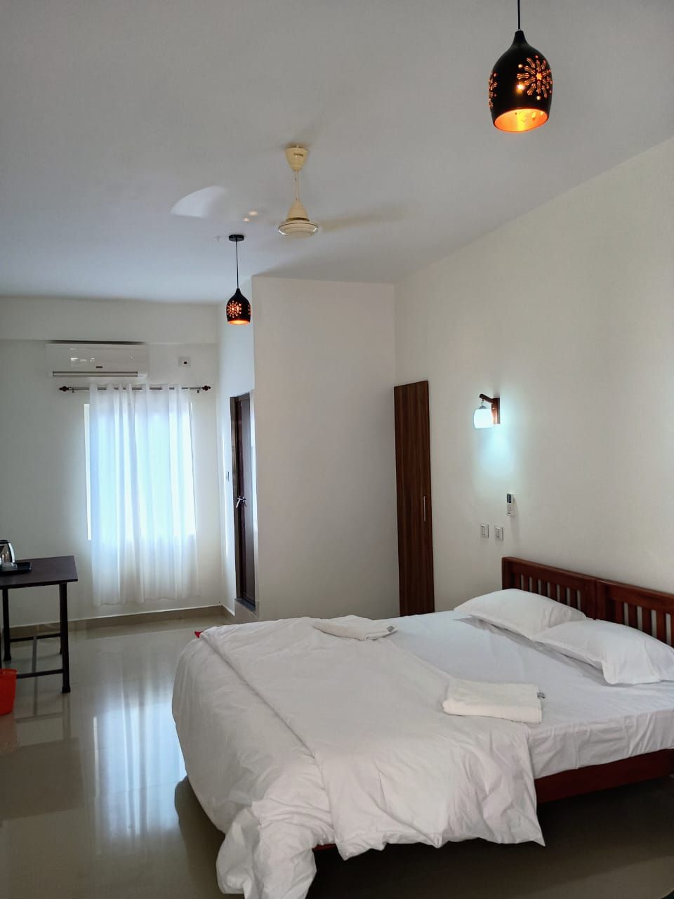 A hotel room with a bed, a desk, and a ceiling fan.
