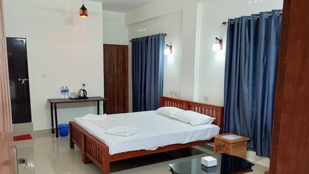 Une chambre d’hôtel avec un lit en bois, une petite table, un bureau et une chaise.