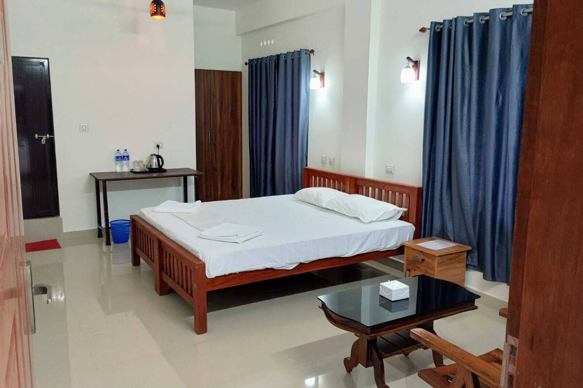 A hotel room with a wooden bed, a small table, a desk, and a chair.