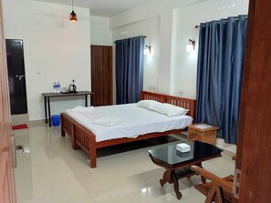 A hotel room with a wooden bed, a small table, a desk, and a chair. - Chael Residency Cochin (Aluva)