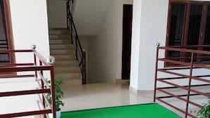 Une pièce spacieuse avec un tapis vert, un escalier en bois et une rampe en métal.