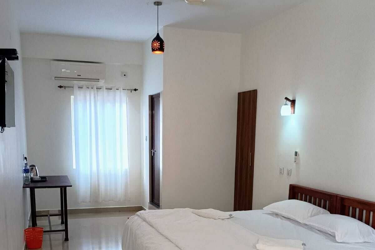A hotel room with a large bed, a desk, a chair, and a ceiling fan.
