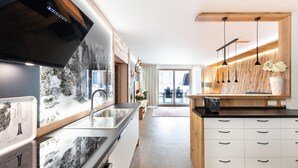 A modern kitchen with a large island, stainless steel appliances, and wooden accents. - Lively apartment near the ski slope (Schladming - Rohrmoos)
