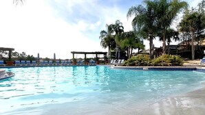 A swimming pool with lounge chairs and palm trees. - Family Oasis, Cozy Retreat With Bunk Room (Kissimmee)