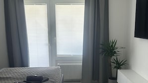 A bedroom with a bed, a radiator, a potted plant, and a TV on the wall. - Vacation apartment Menges (Medebach)