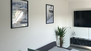 A modern living room with a sofa, two framed pictures, a TV, and a radiator. - Ferienwohnung Juli - neu Renovierte, Moderne Ferienwohnung (Medebach)