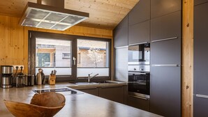 Eine moderne Küche mit Holzbalkendecke, Edelstahlgeräten und einem großen Fenster.