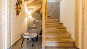 Eine Holztreppe mit Fischgrätmuster, ein Wanddekor und ein gemustertes Stuhl.